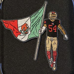 Może przedstawiać: Haftowana naszywka przedstawiająca zawodnika futbolu amerykańskiego w czarnej koszulce z numerem 54, trzymającego meksykańską flagę. Flaga ma czerwone, białe i zielone paski z meksykańskim herbem. Na czarnym tle.