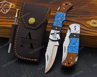 Könnte beinhalten: Ein Messerset mit braunen Holzgriffen, blauen Steinoptik-Akzenten und silbernen Klingen. Das Set enthält eine Ledertasche mit dem Namen "Austin" und ein Schärfwerkzeug. Die Messer tragen den Text "Valor Knife".