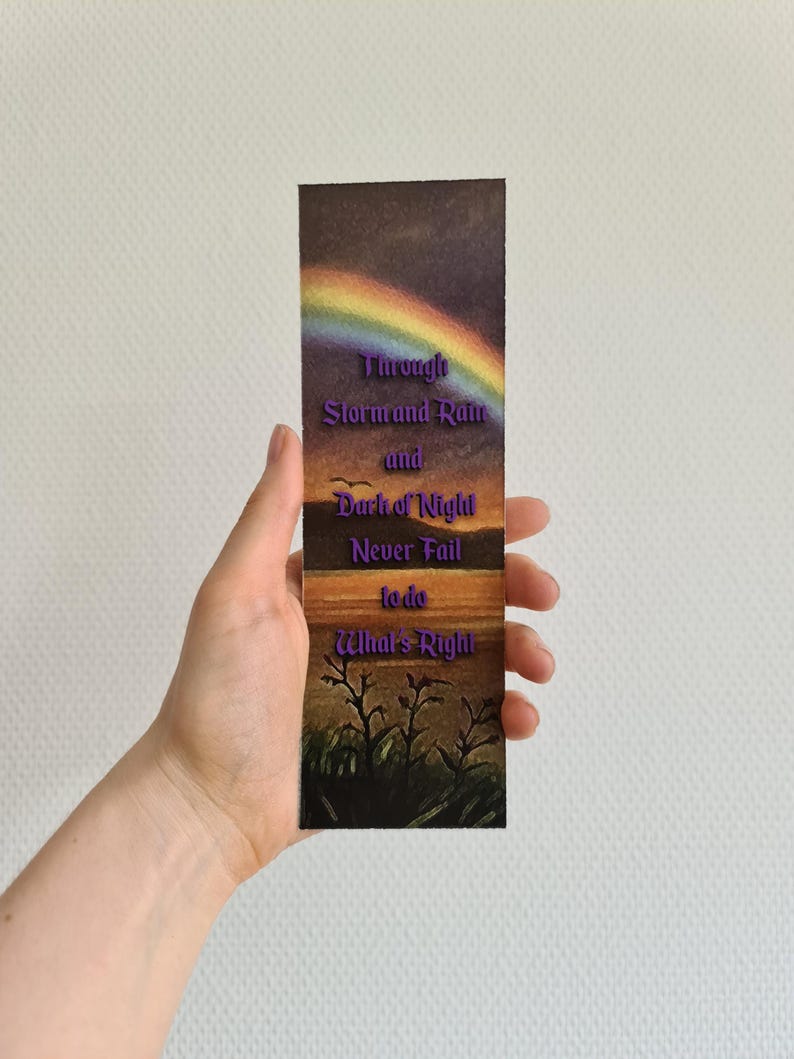Op de afbeelding: Een bladwijzer met een zonsondergangsc&egrave;ne en een regenboog. De tekst op de bladwijzer luidt "Through Storm and Rain and Dark of Night Never Fail to do What's Right."