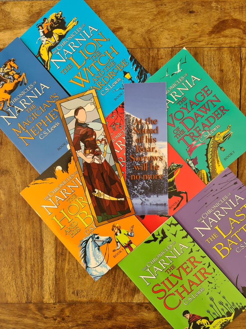 May include: A collection of seven paperback books from the Chronicles of Narnia series by C.S. Lewis. The books are arranged in a semi-circle on a wooden surface. The titles of the books are The Magician's Nephew, The Lion, the Witch and the Wardrobe, The Horse and His Boy, The Voyage of the Dawn Treader, The Silver Chair, and The Last Battle.