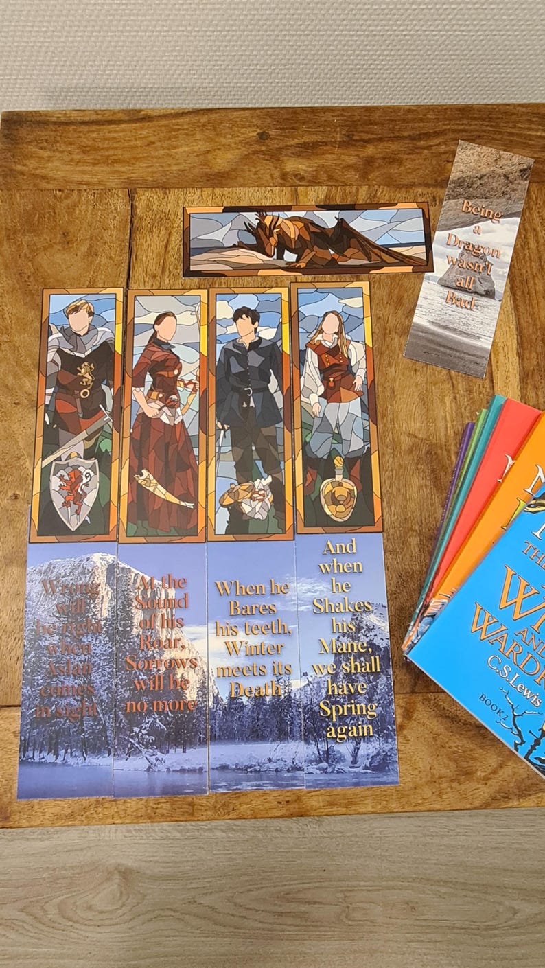 May include: Four colorful bookmarks featuring characters from the book series "The Chronicles of Narnia". The bookmarks have stained glass-like designs and include quotes from the books. The bookmarks are on a wooden surface with a stack of books in the background.