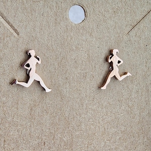 Puede incluir: Un par de pendientes de color dorado con un diseño de silueta de corredor.