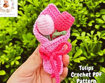 May include: A handmade crochet bouquet of tulips in shades of pink and red, tied with a pink bow. The bouquet includes a light pink tulip, a red tulip, and green leaves. The image also includes the text "Tulips Crochet PDF Pattern".