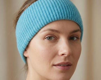 Könnte beinhalten: Ein hellblaues Stirnband mit einer dicken, vertikal gerippten Strickstruktur. Das Accessoire ist so konzipiert, dass es eng am Kopf anliegt und ein gleichmäßiges, strukturiertes Erscheinungsbild auf der gesamten Oberfläche des Strickbandes bietet.