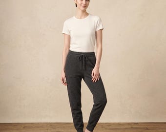 Könnte beinhalten: Ein kurzärmeliges, cremefarbenes T-Shirt mit Rundhalsausschnitt kombiniert mit einer dunkel anthrazitfarbenen Jogginghose. Die Jogginghose verfügt über einen elastischen Bund mit passendem Kordelzug, zwei Seitentaschen und gerippte Bündchen.