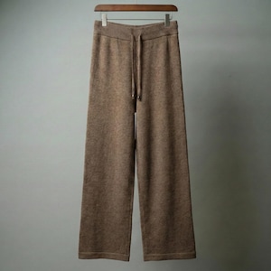 May include: Brown knit wide-leg pants with a drawstring waist, hanging on a wooden hanger. The pants have a relaxed fit and a ribbed waistband. The fabric appears soft and comfortable, suitable for casual wear. The pants are a solid color.