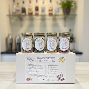 May include: A white box labeled "VODKA OR GIN Cocktail Infusion Box" with four glass jars. Each jar has a gold lid and a label that says "Happy Birthday, cheers!". The box includes ingredients for cocktails.