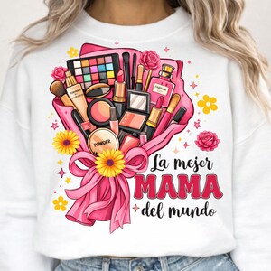 May include: White sweatshirt featuring a pink bouquet of makeup products, including lipstick, eyeshadow, and perfume. The bouquet is tied with a pink ribbon and adorned with yellow flowers and the text "La mejor MAMA del mundo."