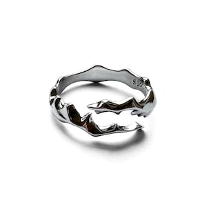 Könnte beinhalten: Ein silberfarbener Ring mit einem organischen, fließenden Design. Der Ring hat einen offenen, verstellbaren Stil mit einer strukturierten Oberfläche. Der Metallring befindet sich auf weißem Hintergrund. Der Ring ist mit "S925" markiert.