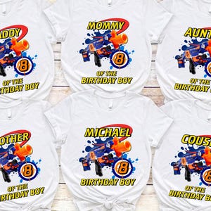 May include: White t-shirts with colorful graphics for a birthday party. Each shirt features a toy gun design, the number 8, and a family member's title, such as "Daddy" or "Cousin".