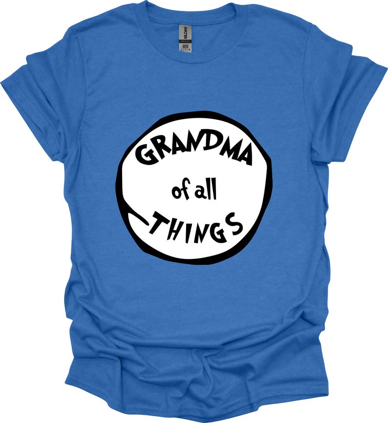 May include: A blue t-shirt with the text "GRANDMA of all THINGS" in a black and white circular design. The shirt is made of a soft material and has short sleeves. The text is in a playful, handwritten style.