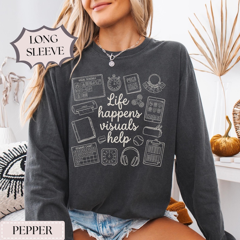 May include: Pepper-colored long-sleeve sweatshirt with a white graphic design. The design includes the text "Life happens visuals help" surrounded by various visual aids. The sweatshirt has a crew neck and is made of a soft material.