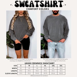 May include: Dark grey unisex crewneck sweatshirt. The image shows a woman wearing a size small and a man wearing a size large. The sweatshirt measurements are provided in inches: width from 21 to 29.5 inches, length from 27.5 to 32.5 inches, and sleeve length from 31.5 to 39.25 inches.