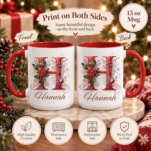 Op de afbeelding: Twee witte keramische mokken met rode binnenkant en oren, elk voorzien van een grote rode letter H versierd met hulst, kerststerren en bessen, met de naam Hannah eronder. Tekst bevat Print on Both Sides en 15 oz Mug.