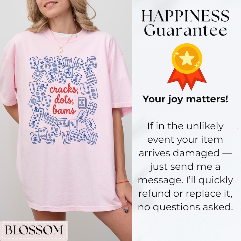 May include: A light pink t-shirt featuring a blue and white graphic of Mahjong tiles with the words "cracks, dots, bams." The shirt also has the word "BLOSSOM" at the bottom.