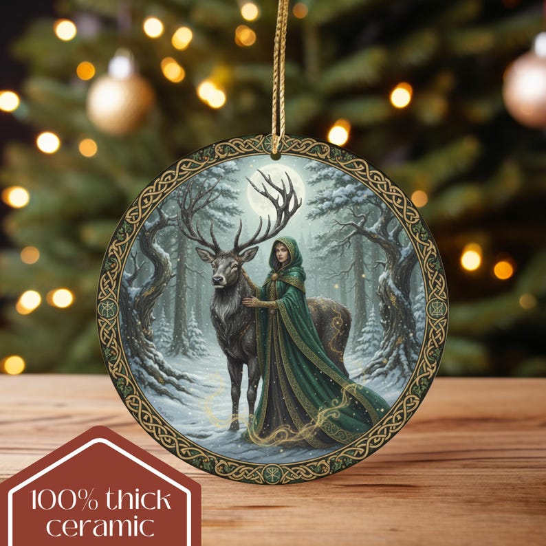May include: Round ceramic Christmas ornament featuring a forest scene with a woman in a green cloak and a stag. The ornament has a gold-colored string for hanging and a decorative Celtic knot border. The text "100% thick ceramic" is at the bottom.