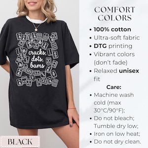 May include: Black t-shirt with a white graphic of Mahjong tiles and the words "cracks, dots, bams." The shirt also has the word "BLACK" at the bottom. The shirt is made of 100% cotton and has a relaxed unisex fit.