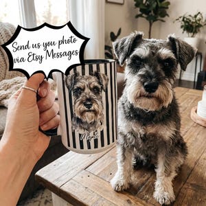 May include: A white ceramic mug with a black interior and handle, featuring a portrait of a Schnauzer dog with the name "Maple" below. The mug has black and white vertical stripes. The text "Send us you photo via Etsy Messages" is in a speech bubble.