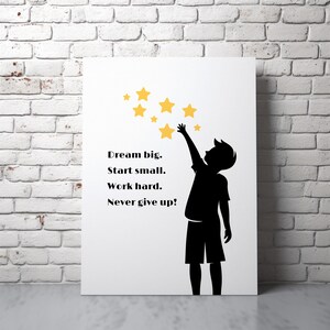 May include: White canvas art print featuring a black silhouette of a child reaching for yellow stars. The text reads "Dream big. Start small. Work hard. Never give up!" The artwork is leaning against a white brick wall.