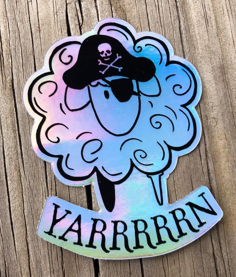 May include: Holographic sticker featuring a sheep with a pirate hat and eye patch. The sheep has a fluffy, cloud-like appearance with the word "YARRRRRN" in a banner below. The sticker has a pearlescent, iridescent finish.
