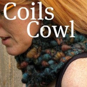 May include: A close-up of a handmade cowl with the text "Coils Cowl" in white. The cowl is a mix of teal, brown, and orange yarns, creating a textured, bobbled appearance. The cowl is around the neck of a person with red hair.