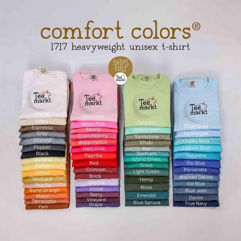 May include: Image of Comfort Colors 1717 heavyweight unisex t-shirts in various colors. The shirts are folded and stacked, with a logo on the front. Colors include white, pink, green, and blue, with a wide range of other shades.