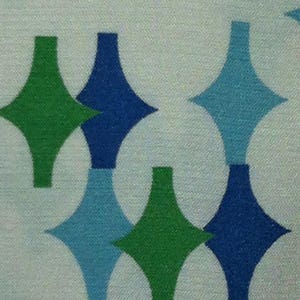 May include: A white fabric with a repeating pattern of green, blue, and light blue diamond shapes.