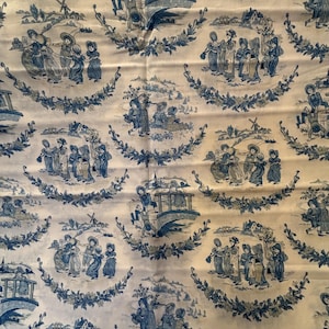 May include: A cream-colored fabric featuring a repeating toile pattern in dark blue ink. The design displays scenes of children playing in rural landscapes, including bridges, windmills, and houses, all framed by circular floral garlands.
