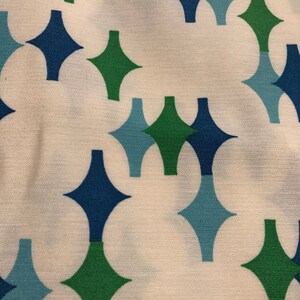 May include: White fabric with a repeating pattern of green, blue, and light blue diamond shapes.