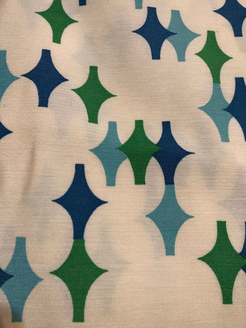 May include: White fabric with a repeating pattern of green, blue, and light blue diamond shapes.