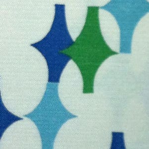 May include: A white fabric with a repeating pattern of blue, green, and light blue diamond shapes.