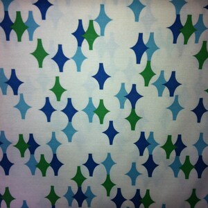 May include: A white fabric with a repeating pattern of blue and green diamond shapes.