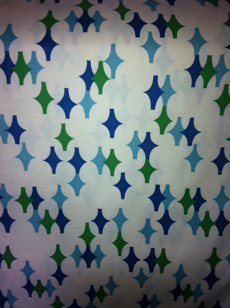 May include: A white fabric with a repeating pattern of blue and green diamond shapes.