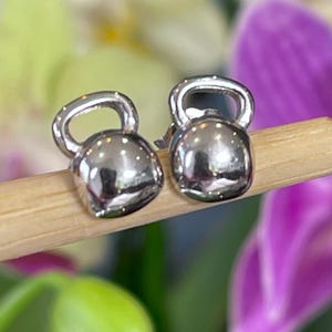 May include: A pair of silver kettlebell earrings. The earrings are small and delicate, and they are perfect for adding a touch of sporty style to any outfit.