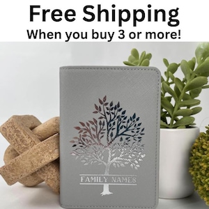 Puede incluir: Un porta pasaporte gris con un diseño de árbol plateado, rojo y azul. El texto "FAMILY NAMES" está debajo del árbol. El texto "Free Shipping When you buy 3 or more!" está en la parte superior.