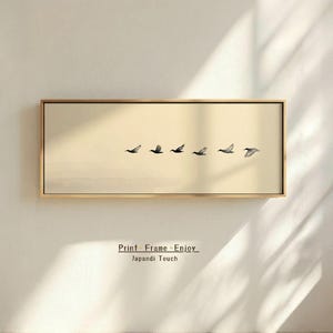 May include: A rectangular framed print featuring a flock of birds in flight against a neutral background. The artwork has a minimalist aesthetic with a warm color palette. The text "Print Frame Enjoy Japandi Touch" is at the bottom.