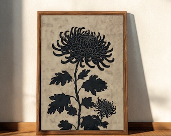 May include: A framed art print showing a black chrysanthemum silhouette on a textured beige backdrop. The botanical illustration is in a wooden frame, leaning against a wall and floor.