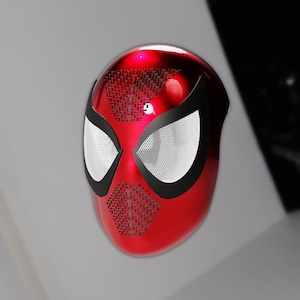 Op de afbeelding: Een rood Spider-Man masker met zwarte accenten rond de ogen en een textuurpatroon aan de bovenkant. De ooglenzen zijn wit met een gaasontwerp. Het masker is glanzend en lijkt van plastic te zijn.