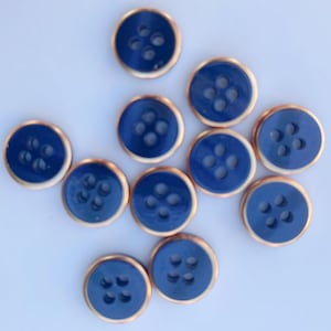 May include: Twelve blue buttons with a copper rim. Each button has four holes.