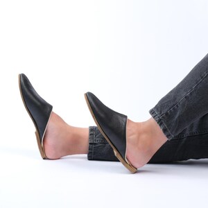 May include: A pair of black leather slip-on shoes with a pointed toe and a brown sole.