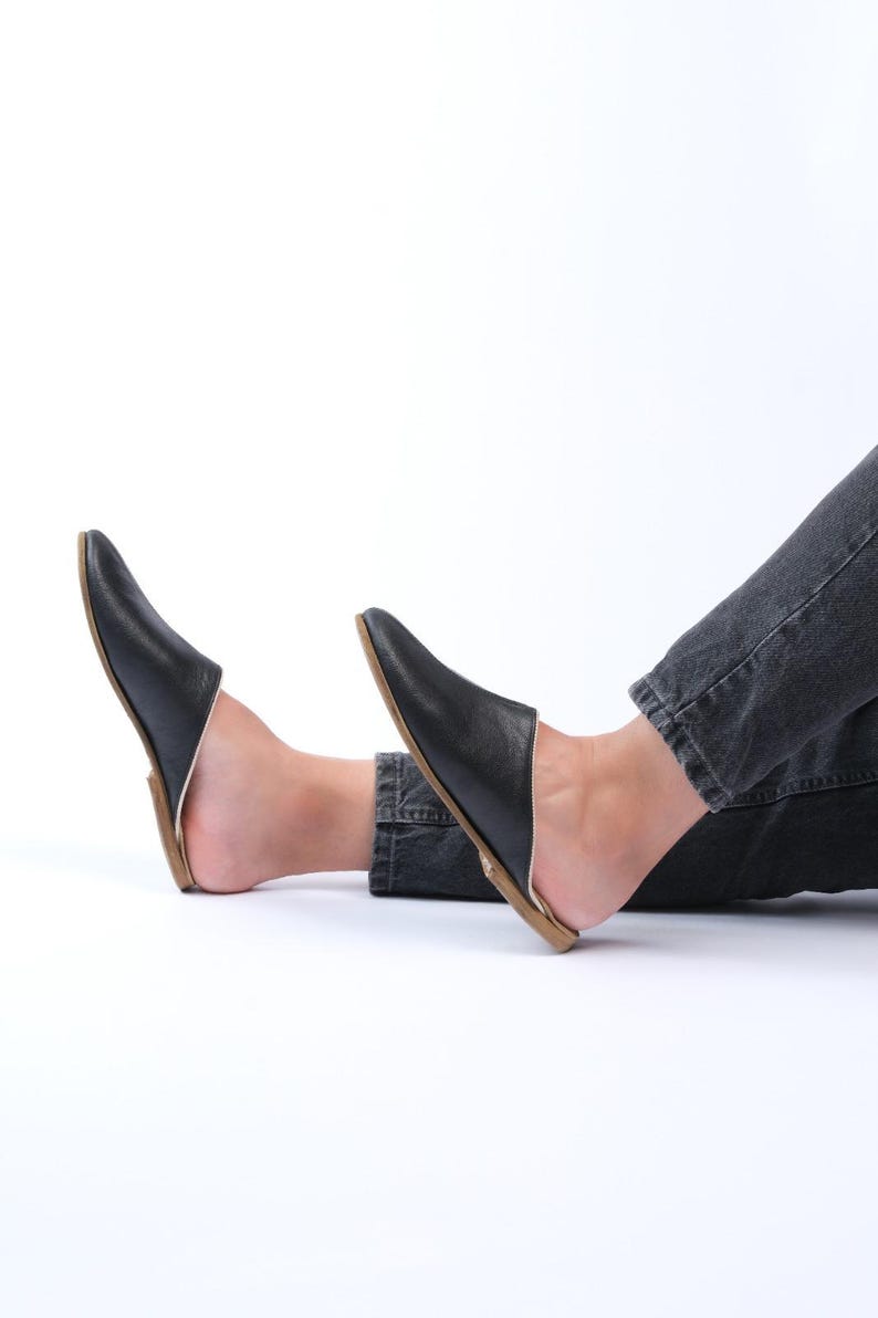 May include: A pair of black leather slip-on shoes with a pointed toe and a brown sole.