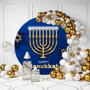 May include: A festive Hanukkah decoration featuring a blue backdrop with a golden menorah and Star of David. The words "Happy Hanukkah" are displayed. Gold, white, and confetti balloons create an arch. Decorative glass and gold accents complete the scene.