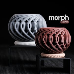 May include: Two spherical planters with an open, woven design. One is gray, the other is a reddish-brown. Both sit on a small, round base. The word "morph" and "planter" are displayed in white and brown text, respectively.