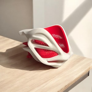 May include: A white 3D printed helmet with a red mesh design. The helmet has a unique, futuristic shape.