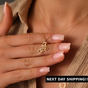 May include: A gold-colored necklace with a cursive letter "A" pendant. The pendant hangs from a delicate chain. The image also includes the text "NEXT DAY SHIPPING!!!".