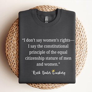May include: A dark gray t-shirt with a white quote from Ruth Bader Ginsburg: "I don't say women's rights - I say the constitutional principle of the equal citizenship stature of men and women."
