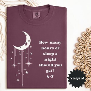 May include: A maroon Comfort Colors t-shirt with a white crescent moon and star design. The shirt features the text "How many hours of sleep a night should you get? 6-7". The tag reads "Vineyard".