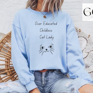 May include: A light blue sweatshirt with the text "Over Educated Childless Cat Lady" and a cartoon cat face.