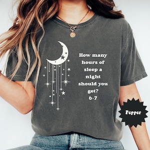 May include: Dark gray t-shirt with a white crescent moon and star design. The shirt has the text "How many hours of sleep a night should you get? 6-7". The word "Pepper" is in a black starburst.
