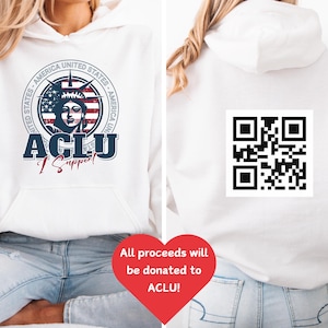 May include: White hooded sweatshirt with a front graphic featuring the Statue of Liberty, the text "ACLU I Support", and a circular design with "America United States" around the edge. The back has a QR code.